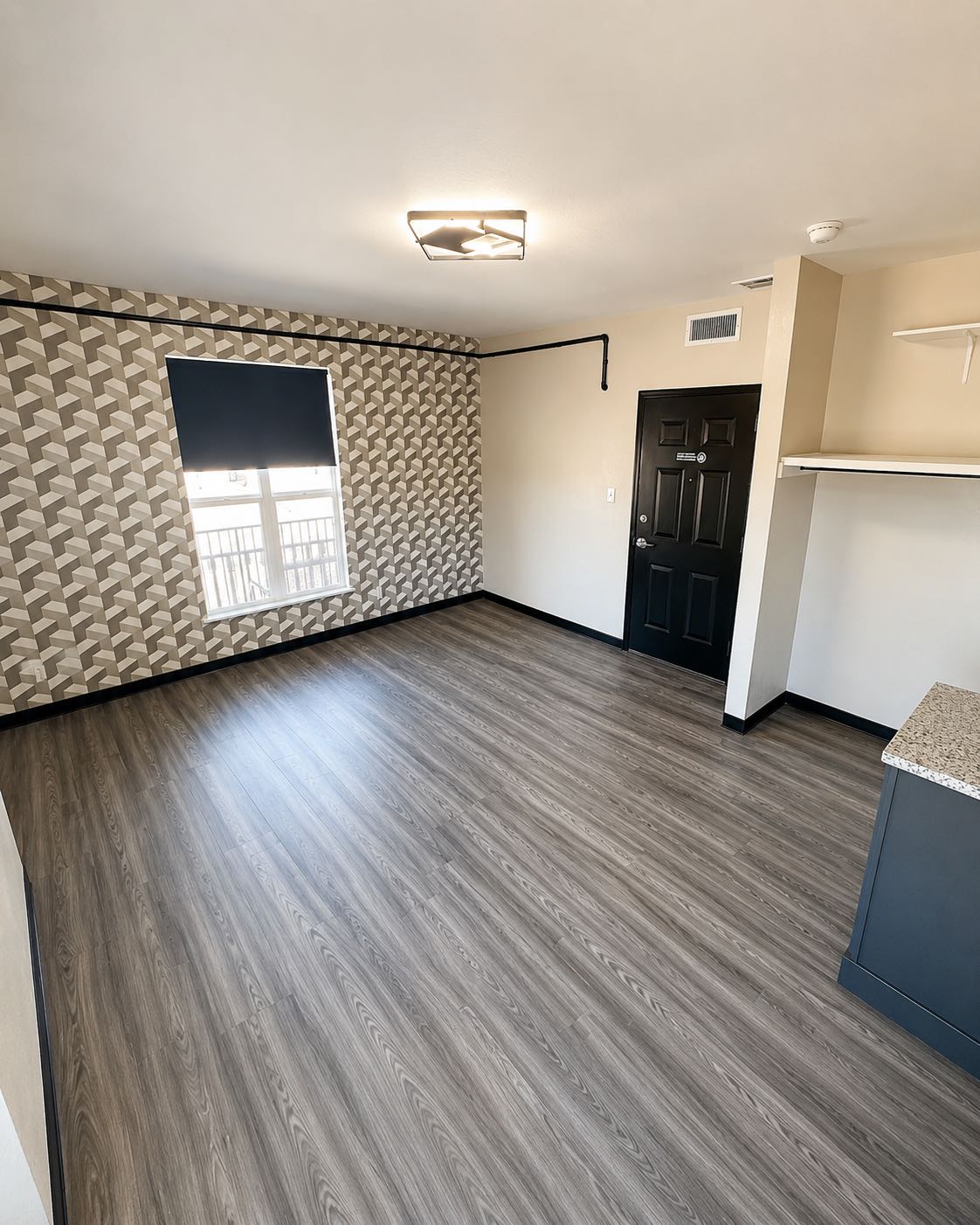 Private residence studio with geometric accent wall, window, and kitchenette